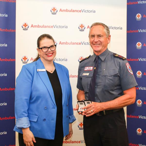 Ambulance Victoria CEO and paramedic Dale Richards stand in front of branded background