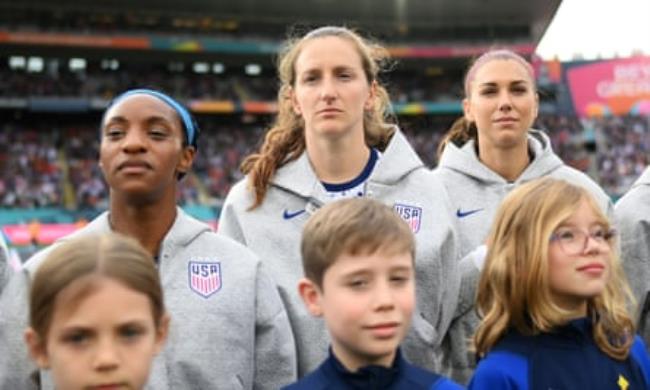 Naomi Girma, Andi Sullivan and Alex Morgan, in USA sweatshirts, stand unsmiling waiting for the natio<em></em>nal anthem