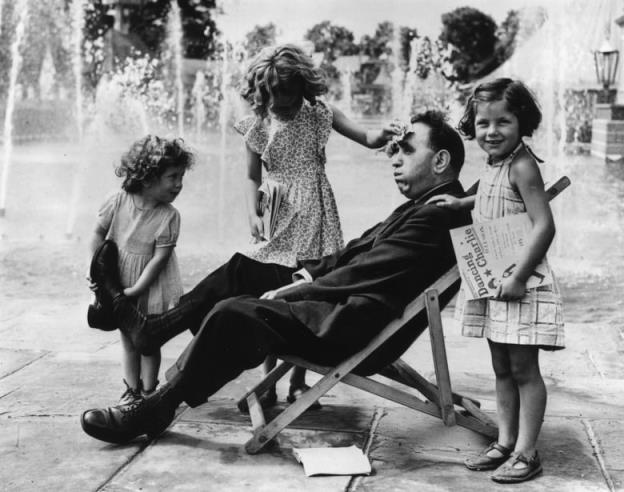 Three little girls pose with their father in this archival black  and  white image